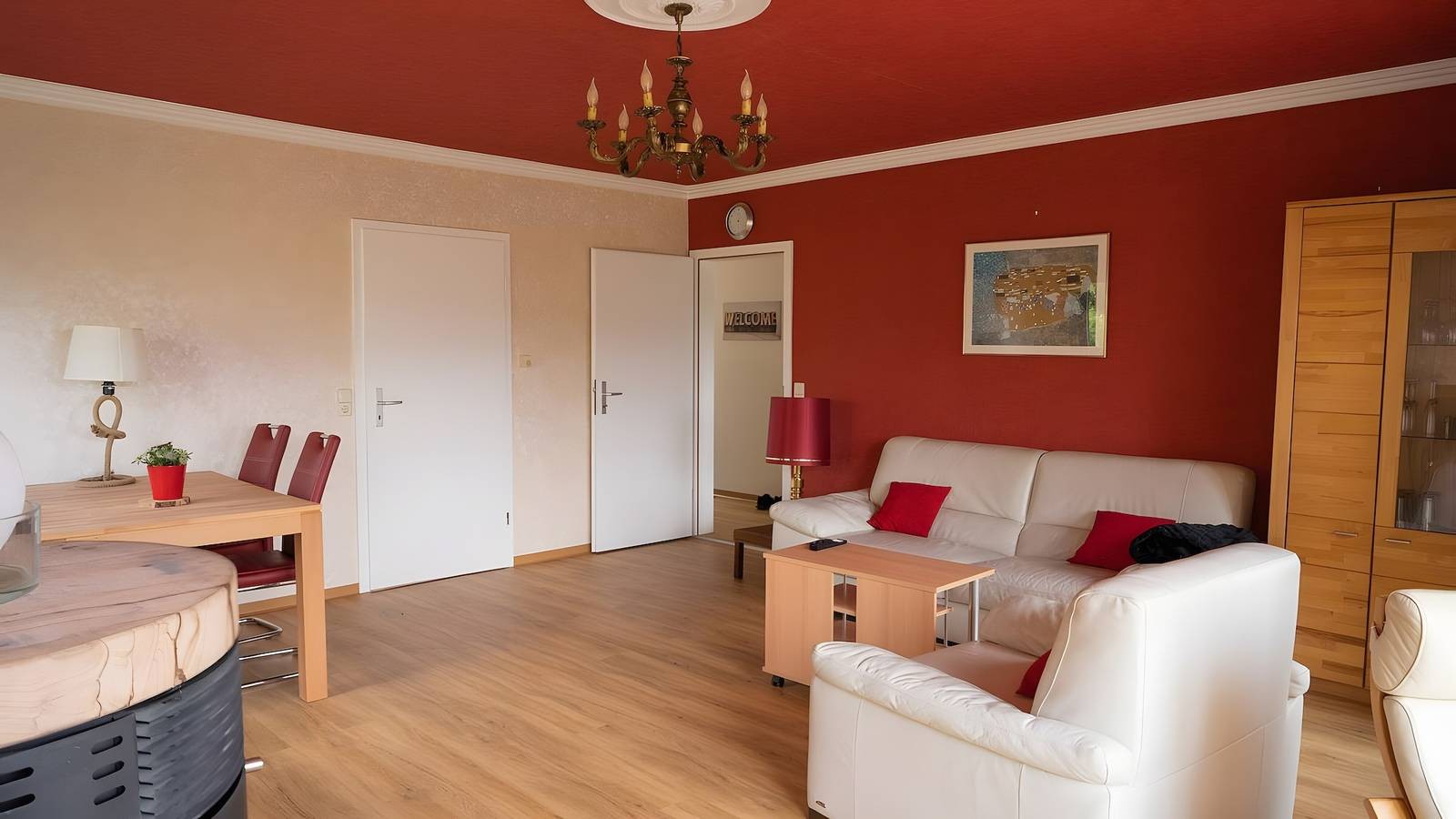 Wohnzimmer mit Ledersofa, Sessel, Vitrine, Esstisch und Kronleuchter
