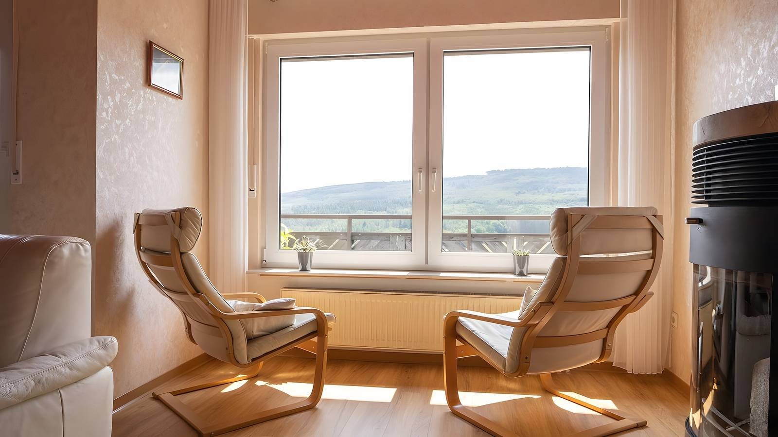 Zwei Schwingsessel vor dem Fenster mit Blick auf die Berge