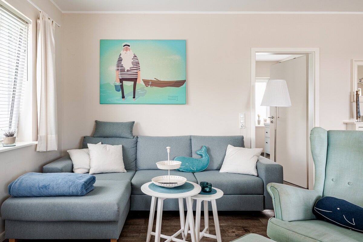 Wohnzimmer mit Ecksofa, Ohrensessel und Beistelltischen