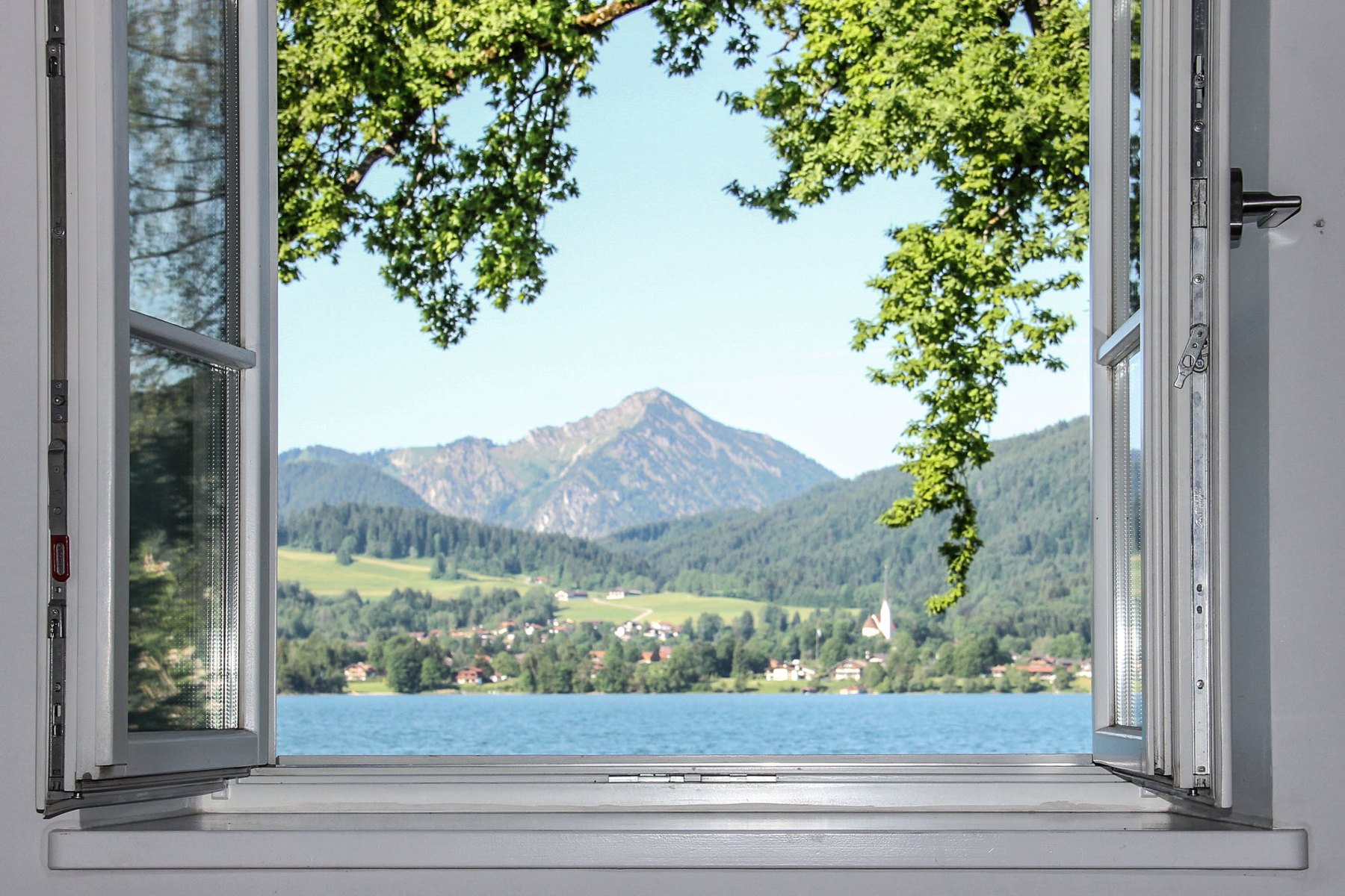 Offenes Fenster mit Blick über den See auf die Berge