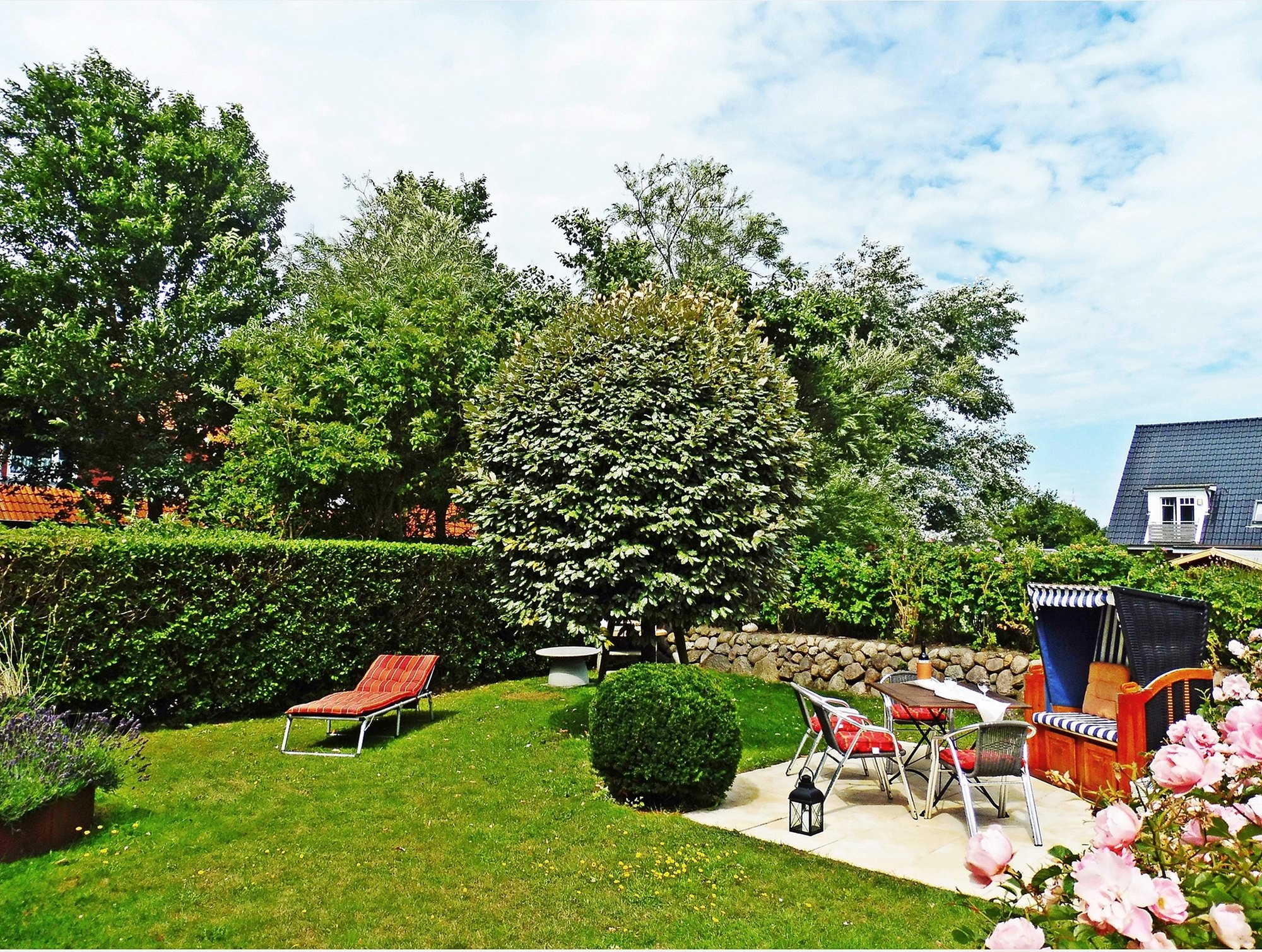 Terrasse mit Strandkorb und Sitzgruppe im Garten