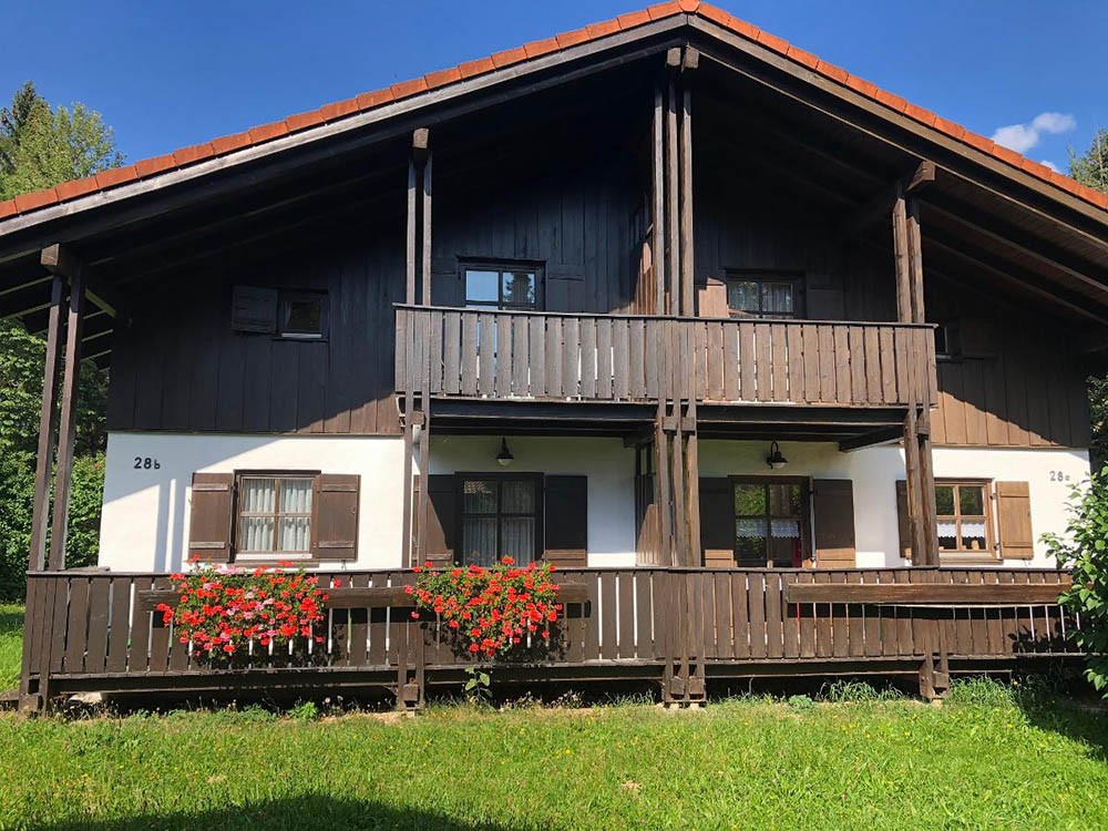 Ferienhaus Walter im Sommer, die linke Doppelhaushälfte mit der Nummer 28b und Geranien am Holzgeländer