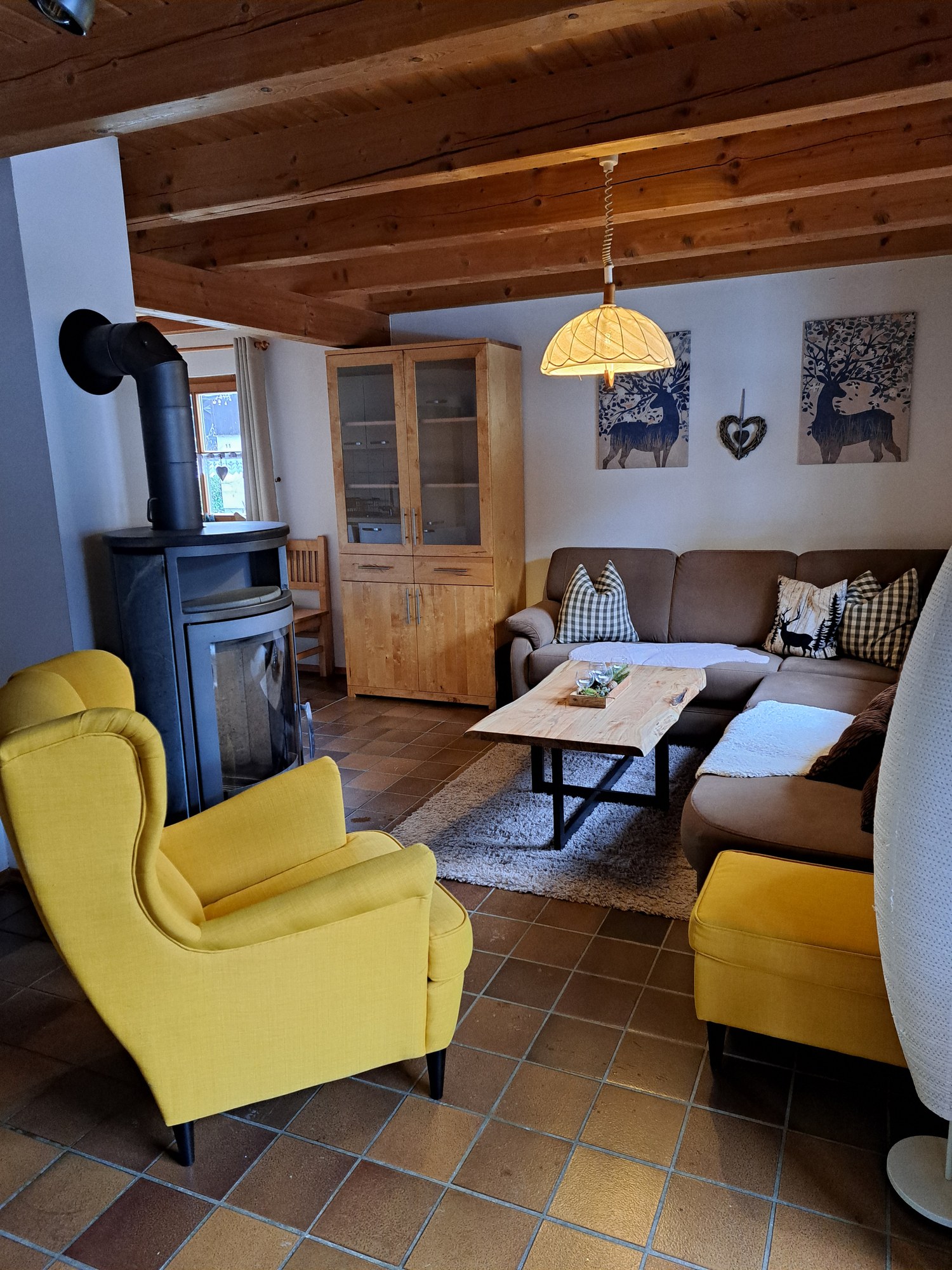 Wohnzimmer mit Kaminofen, gelbem Ohrensessel und Ecksofa