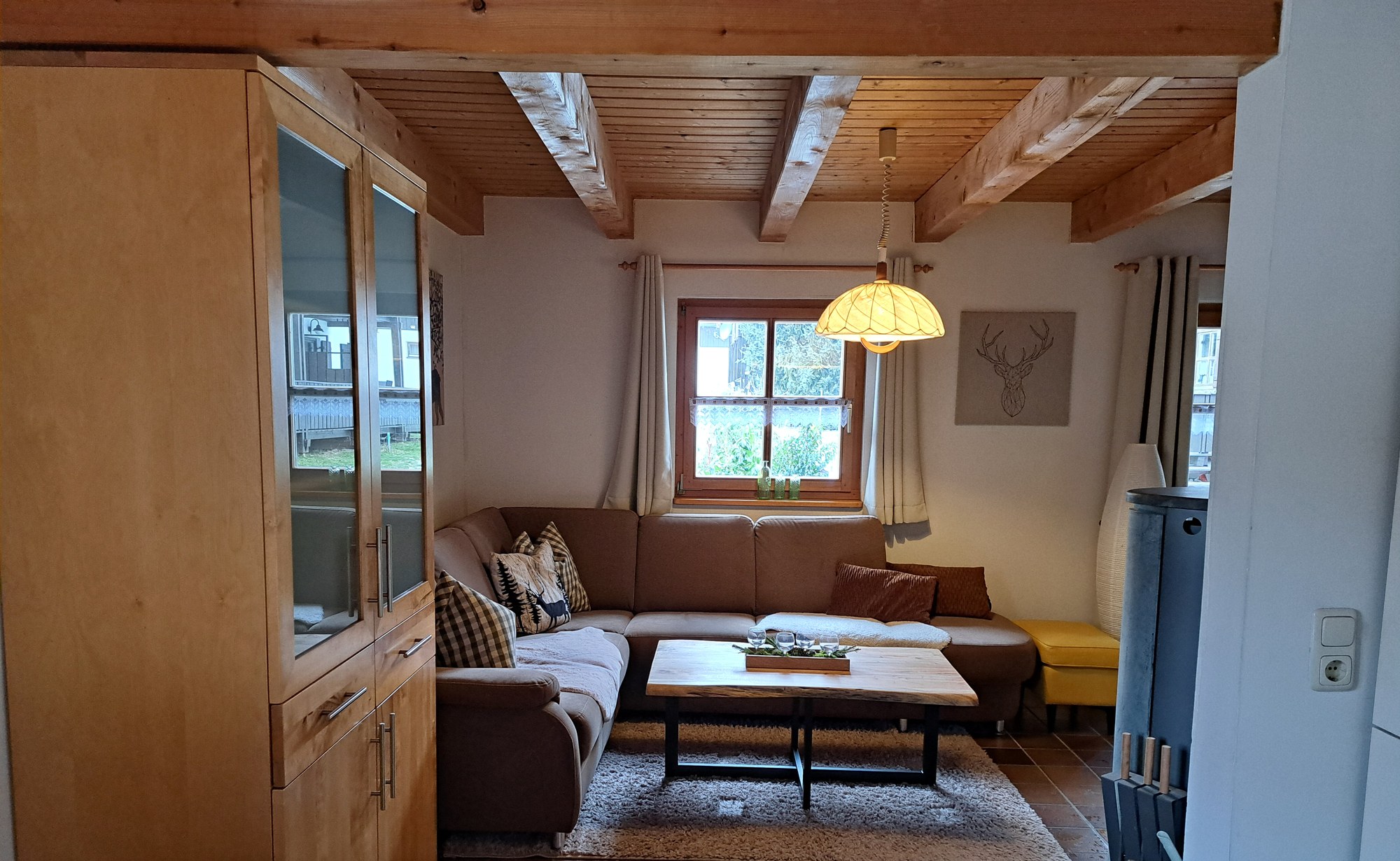 Blick ins Wohnzimmer mit Ecksofa, Couchtisch mit Baumkante und Kaminofen