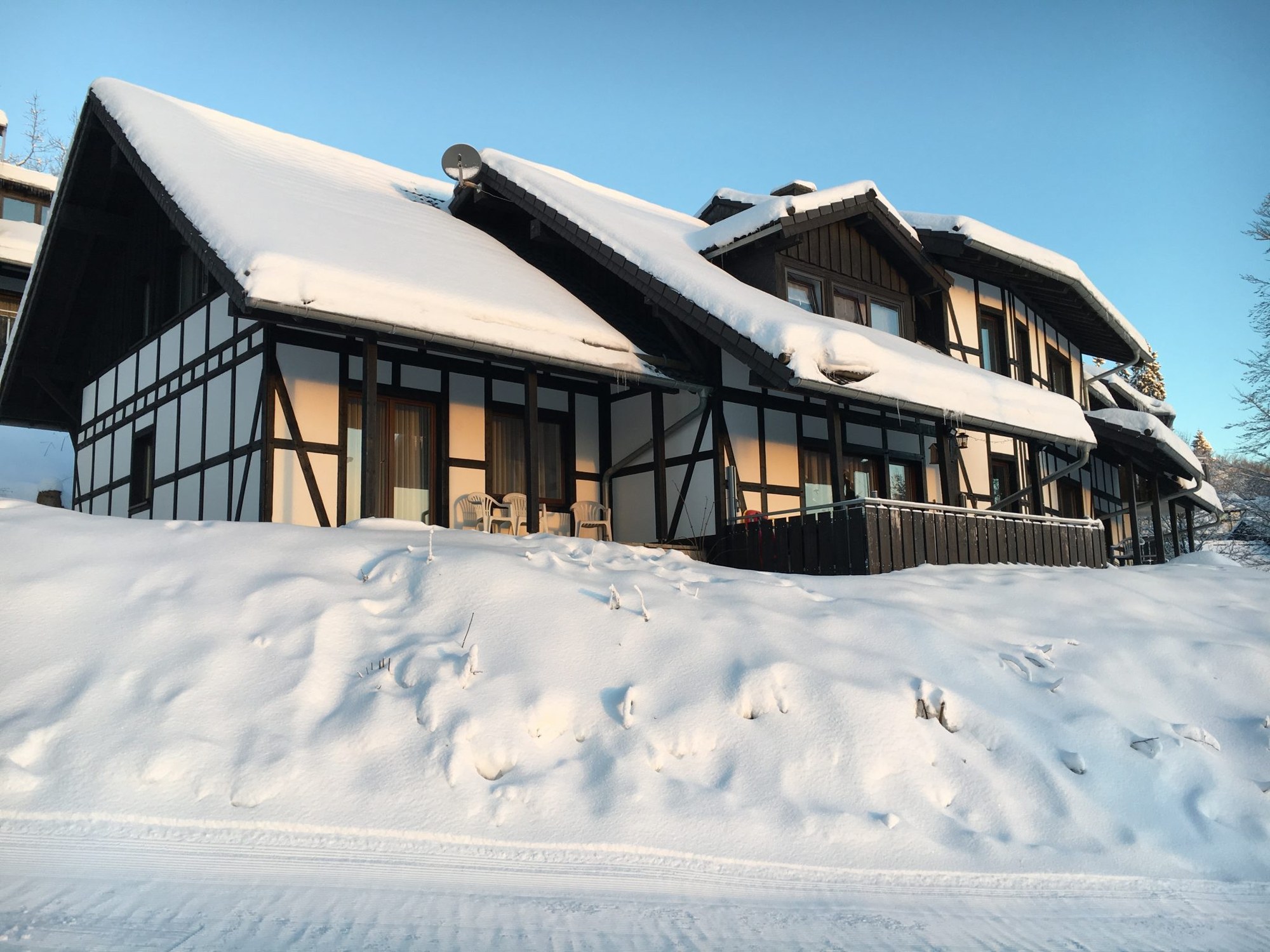 Das Landhaus Postwiese in Neuastenberg bei Winterberg mit den Nachbarhäusern im Winter, von der Rodelbahn aus gesehen