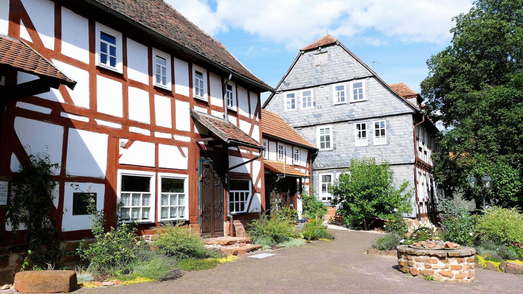 Innenhof der Hofraithe mit altem Brunnen und Fachwerkhäusern im Sommer