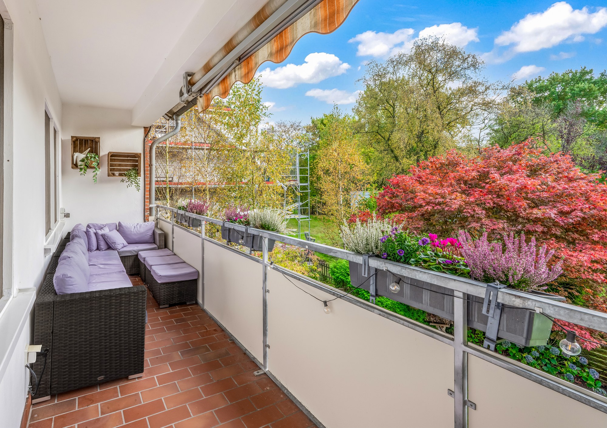 Südbalkon mit Rattan-Lounge und Markise, Blick ins Grüne